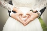 Hochzeit Braut und Brautigam zeigen vor dem Bauch der Braut mit ihren Händen ein Herz